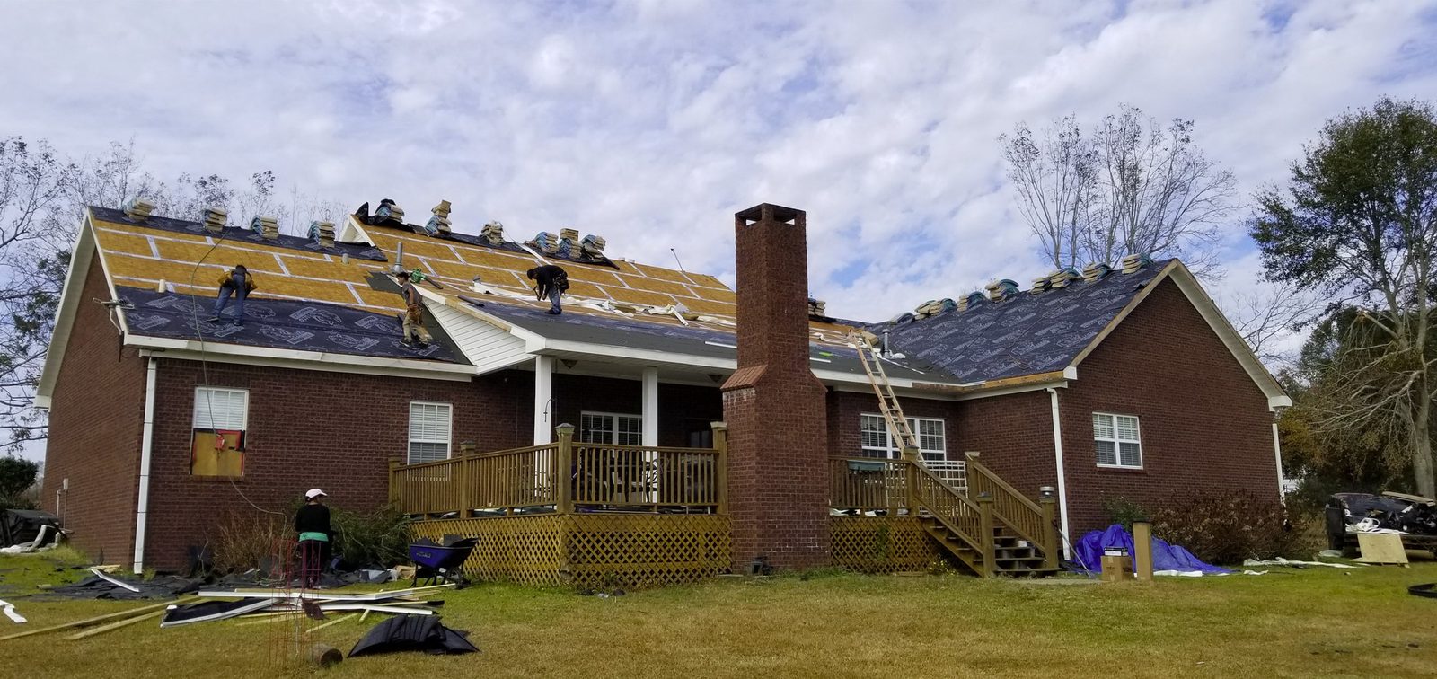 A&W Roofing crew mid tear-off, decking and underlayment going down